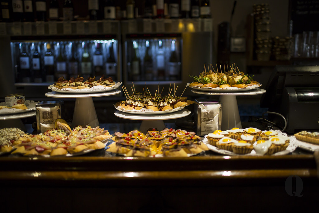 Gandarias 吧台上分层摆放的各式 pintxos，台牌可见店名