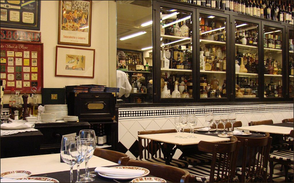 Víctor Montes 餐厅内的酒柜、黑白拼花与铺好餐具的餐桌
